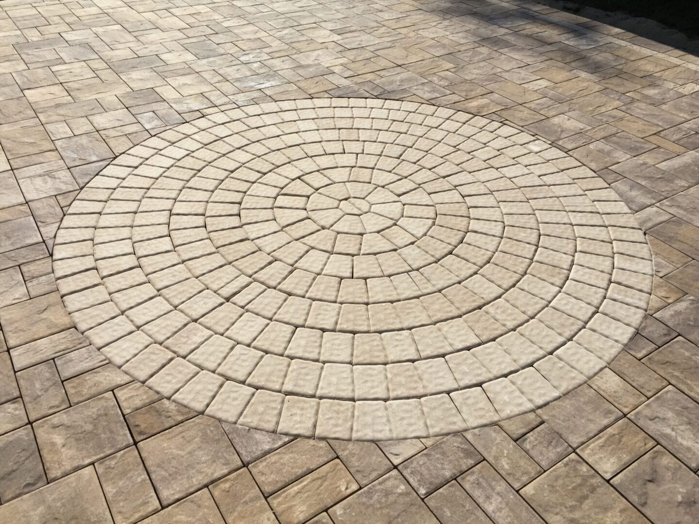 A circular design made of bricks on the floor outside of a place.
